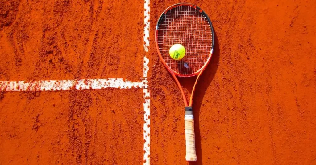 tennis racket and ball on a clay court